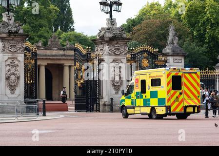 NHS-Krankenwagen kommt am Buckingham Palace Gate, London, Großbritannien, mit bewaffnetem Sicherheitspolizisten. Toröffnung Stockfoto