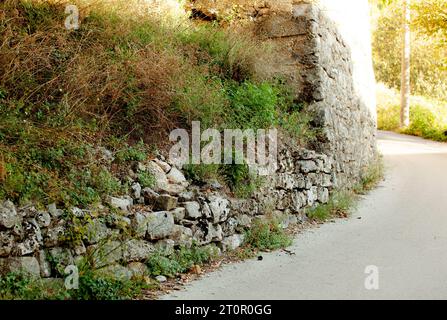 Eine alte Mauer aus Kopfsteinpflaster im Grünen. Eine Straße in Montenegro. Budva. Seoce. Stockfoto