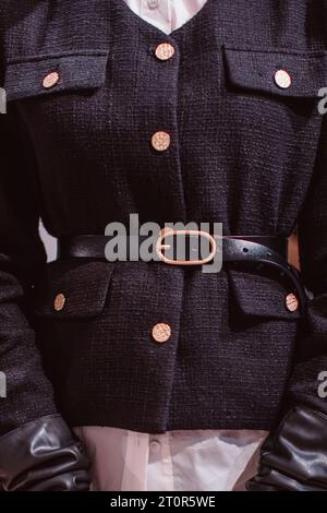 Modische Details einer eleganten schwarzen Jacke, eines Ledergürtels und goldener Knöpfe. Stockfoto