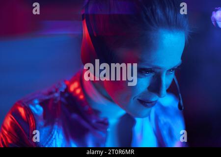 Neon-Metaverse-futuristisches Konzept. Elegante Geschäftsfrau mit Headset, die im modernen Büro Videochat führt. Stockfoto