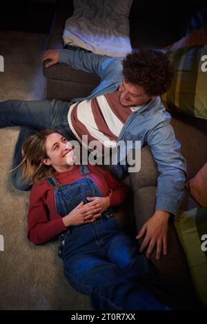 Senkrecht von der Spitze des jungen kaukasischen Paares in Liebe liebevoll sitzend auf Teppich in der Nacht. Stockfoto