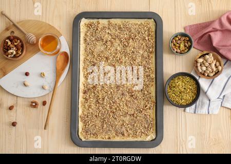 Ich mache köstliche Baklava. Backpfanne mit Teig und Zutaten auf Holztisch, flach liegend Stockfoto