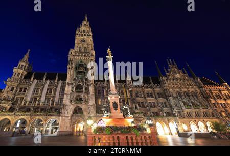 Blick auf das Rathaus mit Uhrenturm auf dem Marienplatz, beleuchtet bei Dämmerung in München, Deutschland Stockfoto