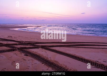 4x4-Reifenspuren am Sandstrand der andamanenküste bei Sonnenuntergang oder Sonnenaufgang über dem Meer, Phuket Island Thailand Stockfoto