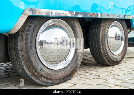 Räder mit glänzenden Scheiben eines großen blauen Food Trucks in der Nähe der Stadtstraße. Fahrzeug mit tragbarem Café für Stadtbesucher. Großes Auto mit Fast Food Stockfoto