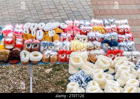 Warme Wollschuhe auf Handwerkskunst auf der Stadtstraße. Pelzpantoffeln und weiche Stiefel werden im Stadtpark verkauft. Kunsthandwerk mit Zubehör Stockfoto