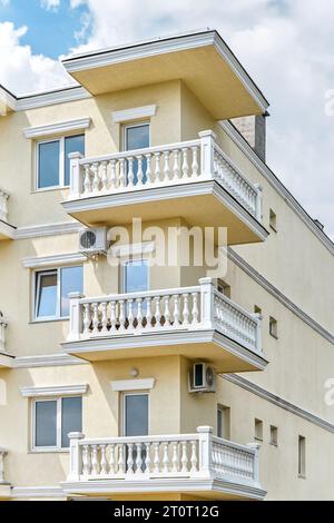 Gebäude mit mehrstöckigen Balkonen, dekoriert mit klassischen Betonzäunen mit Balustern. Eleganter äußerer Teil des Hotelkomplexes Stockfoto