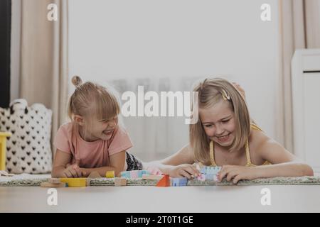 Kinder spielen mit bunten Spielzeugen. Kinder sitzen auf Teppich im Schlafzimmer oder Kindergarten zu Hause. Entwicklung feinmotorischer Fähigkeiten, Vorstellungskraft, logisches Denkkonzept. Umweltfreundliche Lernspiele Stockfoto