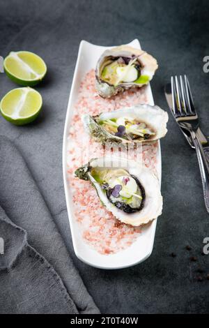 Frische Austern auf rotem Meersalz auf einer weißen Platte Stockfoto