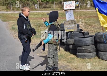 Bilenke, Ukraine. Oktober 2023. Kinder, die vorgeben, territoriale Verteidigungskämpfer zu sein, werden an ihrem Spielkontrollpunkt im Dorf Bilenke in der Region Zaporischschhia gesehen. Alle ukrainischen Kinder sind tief vom Krieg betroffen. Viele haben ihr Leben radikal verändert, weil sie ihre Häuser verloren haben oder gezwungen wurden, zu evakuieren. Quelle: SOPA Images Limited/Alamy Live News Stockfoto