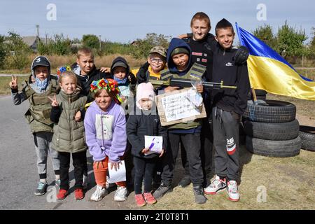 Bilenke, Ukraine. Oktober 2023. Kinder, die sich als territoriale Verteidigungskämpfer ausgeben, posieren an ihrem Spielkontrollpunkt im Dorf Bilenke in der Region Zaporischschhia. Alle ukrainischen Kinder sind tief vom Krieg betroffen. Viele haben ihr Leben radikal verändert, weil sie ihre Häuser verloren haben oder gezwungen wurden, zu evakuieren. Quelle: SOPA Images Limited/Alamy Live News Stockfoto