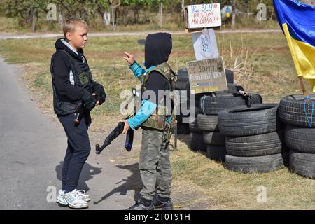 Bilenke, Ukraine. Oktober 2023. Kinder, die vorgeben, territoriale Verteidigungskämpfer zu sein, werden an ihrem Spielkontrollpunkt im Dorf Bilenke in der Region Zaporischschhia gesehen. Alle ukrainischen Kinder sind tief vom Krieg betroffen. Viele haben ihr Leben radikal verändert, weil sie ihre Häuser verloren haben oder gezwungen wurden, zu evakuieren. (Foto: Andriy Andriyenko/SOPA Images/SIPA USA) Credit: SIPA USA/Alamy Live News Stockfoto