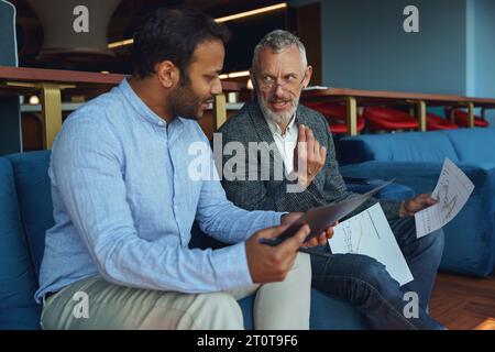 Zwei Geschäftskollegen diskutieren das Projekt, bevor sie dem Teamleiter im Büro eine Präsentation zeigen Stockfoto