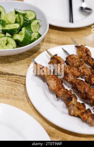 Ein Teller mit Lammspießen und einer Beilage mit Gurkensalat im Appandim Uyghur Restaurant in Burwood - Sydney, NSW, Australien Stockfoto