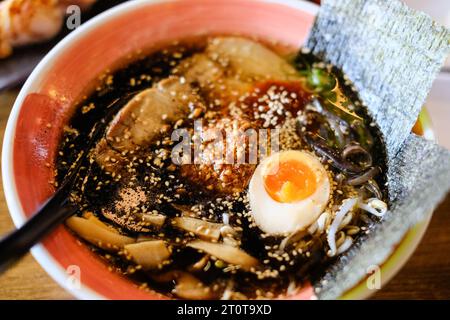 Eine Schüssel Tonkotsu-Ramen mit schwarzem Knoblauchöl, gegrillten Chashu-Scheiben, Bambussprossen und weichgekochtem Ei im japanischen Restaurant Mikazuki in Sydney Stockfoto
