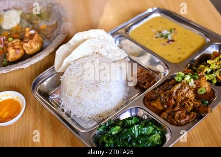 Chicken Daal Baht Power (Reis, Spinat, Linsen, Gurke & Hühnercurry) serviert auf einem Edelstahltablett in einem nepalesischen Restaurant in Sydney Stockfoto