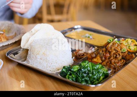 Chicken Daal Baht Power (Reis, Spinat, Linsen, Gurke & Hühnercurry) serviert auf einem Edelstahltablett in einem nepalesischen Restaurant in Sydney Stockfoto