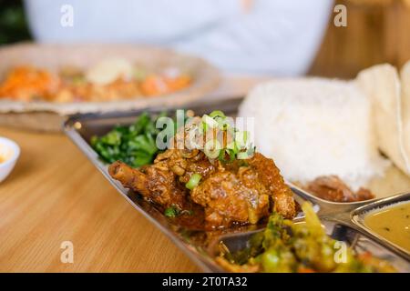 Chicken Daal Baht Power (Reis, Spinat, Linsen, Gurke & Hühnercurry) serviert auf einem Edelstahltablett in einem nepalesischen Restaurant in Sydney Stockfoto