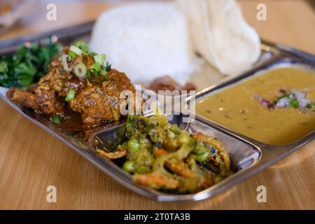 Chicken Daal Baht Power (Reis, Spinat, Linsen, Gurke & Hühnercurry) serviert auf einem Edelstahltablett in einem nepalesischen Restaurant in Sydney Stockfoto