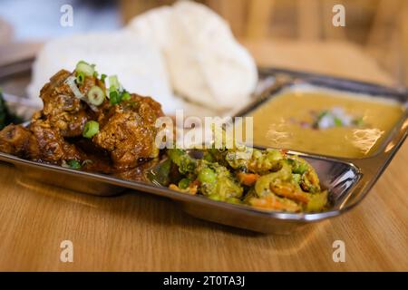 Chicken Daal Baht Power (Reis, Spinat, Linsen, Gurke & Hühnercurry) serviert auf einem Edelstahltablett in einem nepalesischen Restaurant in Sydney Stockfoto