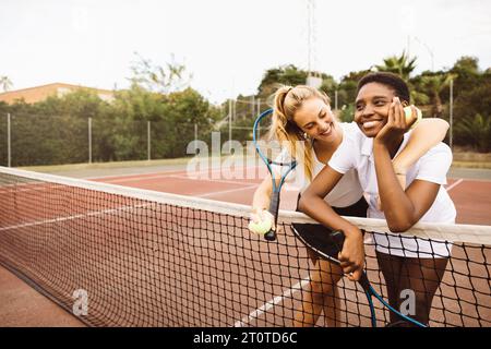 Porträt von zwei jungen schönen Frauen mit Tenniskleidung und Schlägern auf einem Tennisplatz, bereit für ein Spiel. Stockfoto