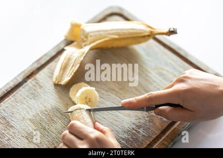 Eine Frau schneidet eine Banane auf einem Schneidebrett. Stockfoto