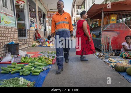 Sigatoka Fidschi - 8. September 2023; Mann in orangefarbener Arbeiterweste geht im Bad zwischen Produkten, die auf Plastikfolien zum Verkauf gelegt sind. Stockfoto