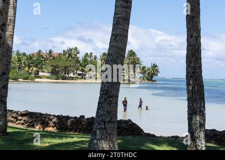 Yanuca Island Fidschi - 6. September 2023; Küstenszene durch Palmenstämme mit Jungen im Wasser, die Fische spinnen Stockfoto