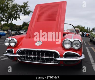 Ein klassisches rotes Cabriolet mit offener Motorhaube, das auf einem Asphaltparkplatz geparkt ist und fahrbereit ist Stockfoto