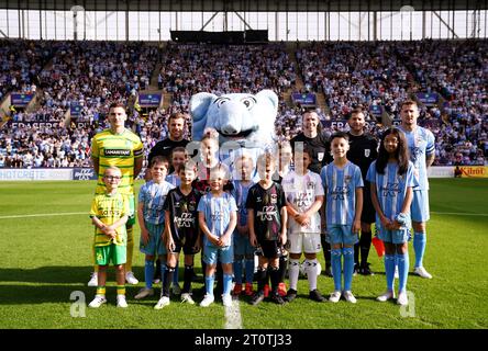 Kyle McFadzean von Coventry City (rechts), Kenny McLean von Norwich City (links), die Spieloffiziere und Maskottchen am Spieltag posieren für ein Foto mit Sky Blue Sam vor dem Sky Bet Championship Match in der Coventry Building Society Arena in Coventry. Bilddatum: Samstag, 7. Oktober 2023. Stockfoto