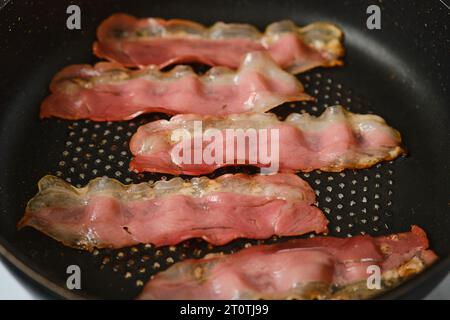 Braten von Speck in einer Pfanne zu Hause Stockfoto