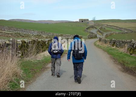 Zwei Männer (Wanderer) auf der Country Lane in der Nähe von Little Stainforth in Ribblesdale, Yorkshire Dales National Park, England, Großbritannien. Stockfoto