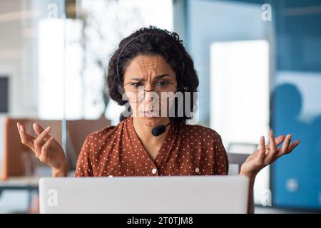 Unzufriedene und traurig enttäuschte Geschäftsfrau mit Headset-Telefon im Büro, Support-Mitarbeiter, müde mit Laptop für Videoanrufe und Online-Kundenberatung. Stockfoto