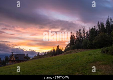 Wunderschöner, dramatischer farbiger Himmel über einer Wiese in den Bergen Stockfoto