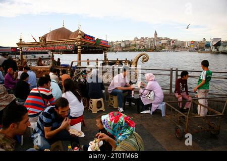 Leute essen frisch gebratene Fisch-Sandwiches, die auf einem Boot in Eminonu zubereitet werden. Istanbul, Türkei. Stockfoto