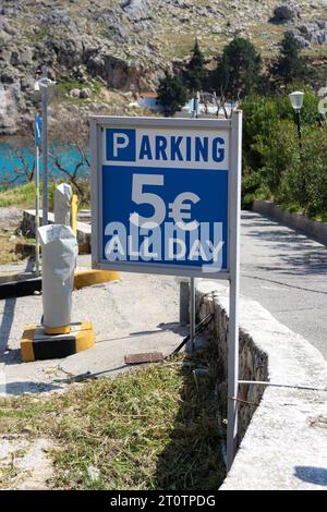 Ein Parkschild informiert die Fahrer über eine Gebühr von 5 € für den ganztägigen Parken am Strand von St. Paul's Bay auf Rhodos, Griechenland Stockfoto