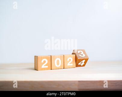 2024 Countdown für ein frohes neues Jahr mit Wechsel zu neuen Konzepten. Die Kalendernummern von 2023 bis 2024 Jahren auf Holzwürfelblöcken umkehren, die auf Holz isoliert sind Stockfoto
