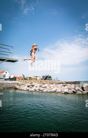 Frau, die vom Hochtauchen in Dänemark ins Meer springt Stockfoto