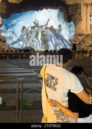 Zwei junge Liebende umarmen sich vor dem Palais Garnier in Paris Frankreich. Der französische Artrist JR umwickelte ein Gerüst an die Außenseite, um ein riesiges Gebäude zu repräsentieren Stockfoto