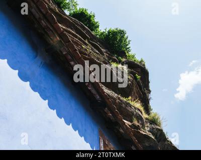 An einem sonnendurchfluteten Tag unter klarem Himmel hebt sich die blaue Fassade der Höhlenfelshäuser in Graufthal, Eschbourg, Unterrhein, Elsass, Frankreich hervor Stockfoto