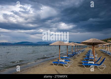 Kalamaki, Korfu, Griechenland - Sonnenliegen und Sonnenschirme am Kalamaki Strand im Nordosten der griechischen Insel Korfu. Hinter dem Festland Albanien. Stockfoto