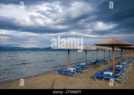 Kalamaki, Korfu, Griechenland - Sonnenliegen und Sonnenschirme am Kalamaki Strand im Nordosten der griechischen Insel Korfu. Hinter dem Festland Albanien. Stockfoto