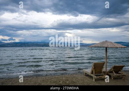 Kalamaki, Korfu, Griechenland - Sonnenliegen und Sonnenschirme am Kalamaki Strand im Nordosten der griechischen Insel Korfu. Hinter dem Festland Albanien. Stockfoto