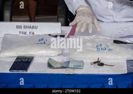 Kendari, Indonesien. Oktober 2023. BNN Sultra Offiziere zeigen zusammen mit Bargeld und anderen Gegenständen, die beschlagnahmt wurden, Beweise für Drogen vom Typ Methamphetamin in Plastikverpackungen im BNN Sultra Büro. Der Nationalen Suchtstoffbehörde (BNN) der Provinz Südosten Sulawesi gelang es, drei Verdächtige im Falle des Schmuggels von Methamphetamin mit einem Gewicht von 1 Kilo, 500 Gramm und 10 Gramm an zwei verschiedenen Orten festzunehmen. (Foto: Andry Denisah/SOPA Images/SIPA USA) Credit: SIPA USA/Alamy Live News Stockfoto