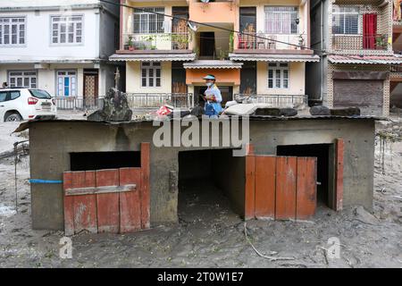 Rangpo, Indien. Oktober 2023. Eine Frau geht an einem Haus vorbei, das in Trümmern getaucht ist, die durch Sturzfluten nach einem Seebiss verursacht wurden. Nachdem ein Gletschersee im Nordosten Indiens kurz nach Mitternacht durch einen Damm platzte, Häuser und Brücken wegspülte und Tausende zur Flucht zwang, gruben die Rettungskräfte weiter durch Schlammschutt. Quelle: SOPA Images Limited/Alamy Live News Stockfoto