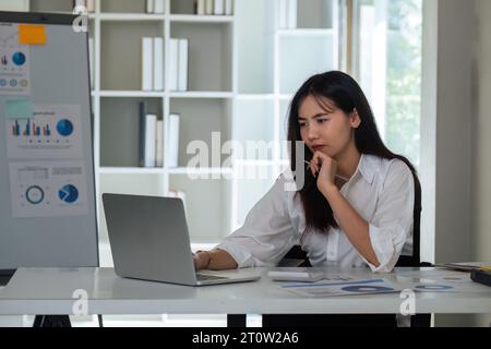 Überarbeitete Geschäftsfrau Finanzierin, während sie im Büro an Notebooks und Tablets arbeitet Stockfoto