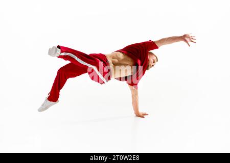 Modisches Porträt. Stilvoll gekleideter Mann, der Freestyle-Tanz vorführt, steht auf Kopf am Tanzsaal vor weißem Studio-Hintergrund. Stockfoto