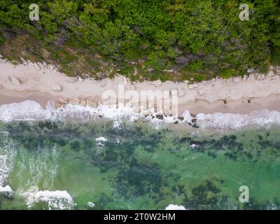 Von oben entfaltete sich der faszinierende Strand mit goldenem Sand, der von türkisfarbenen Wellen gestreichelt wurde. Üppig grüne Wälder schmücken die Küste, während robuste Felsen Stockfoto