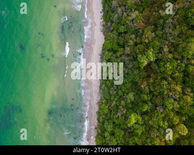 Von oben entfaltete sich der faszinierende Strand mit goldenem Sand, der von türkisfarbenen Wellen gestreichelt wurde. Üppig grüne Wälder schmücken die Küste, während robuste Felsen Stockfoto