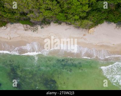 Von oben entfaltete sich der faszinierende Strand mit goldenem Sand, der von türkisfarbenen Wellen gestreichelt wurde. Üppig grüne Wälder schmücken die Küste, während robuste Felsen Stockfoto